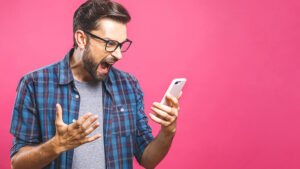 A man yelling at his phone after receiving too many spam text messages.