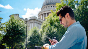 A man standing in front of a government building receiving a tax notification. 