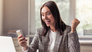 A property manager using sms marketing for internal communication while sitting at her desk looking at her mobile phone. 